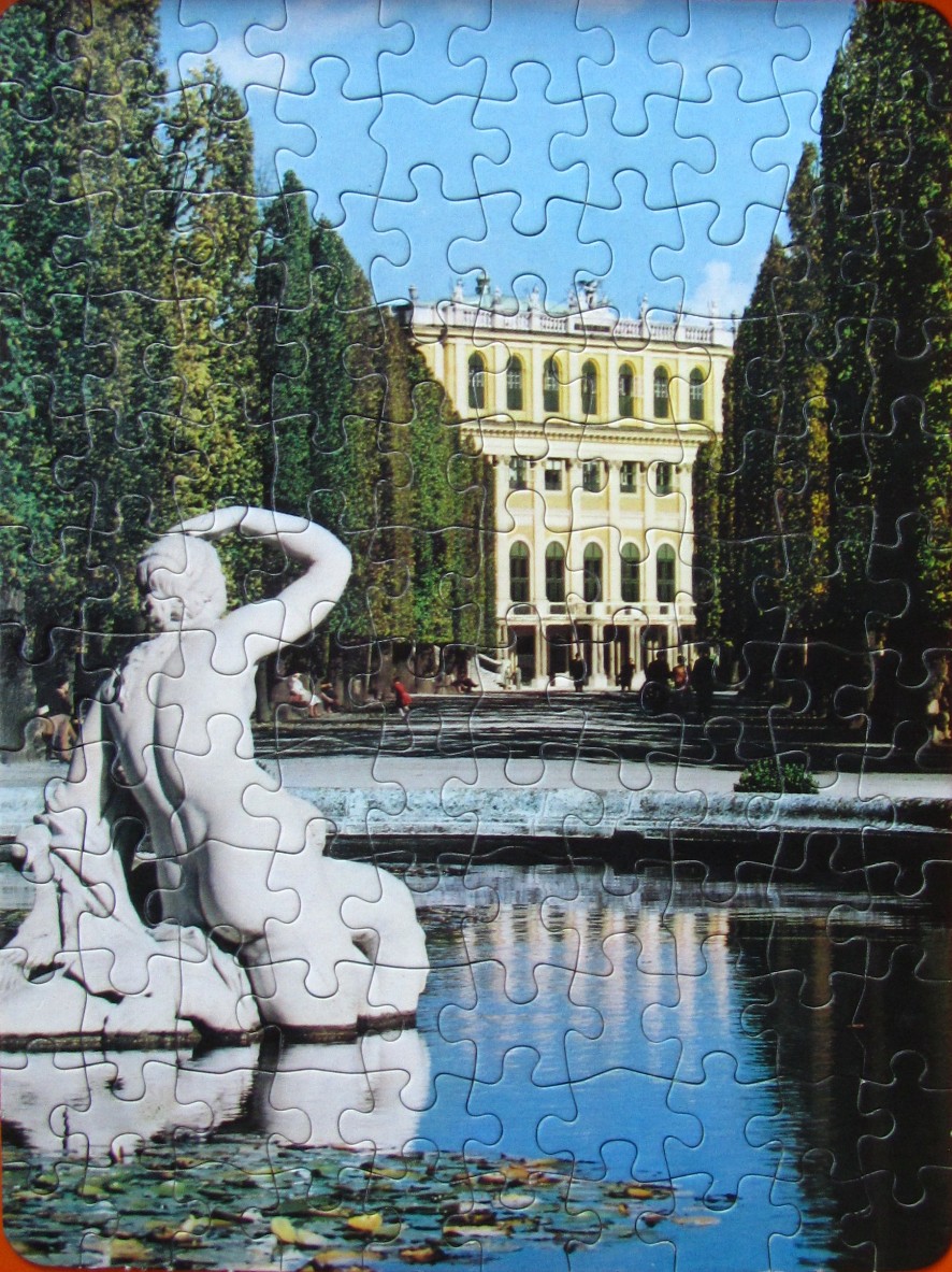 A marble statue overlooks a pond with a grand yellow mansion in the background framed by tall trees.