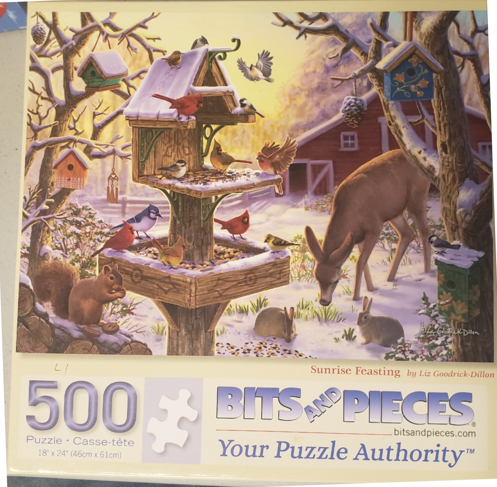 A winter scene featuring a large tiered bird feeder surrounded by birds, a deer, and rabbits in a snowy farmyard.