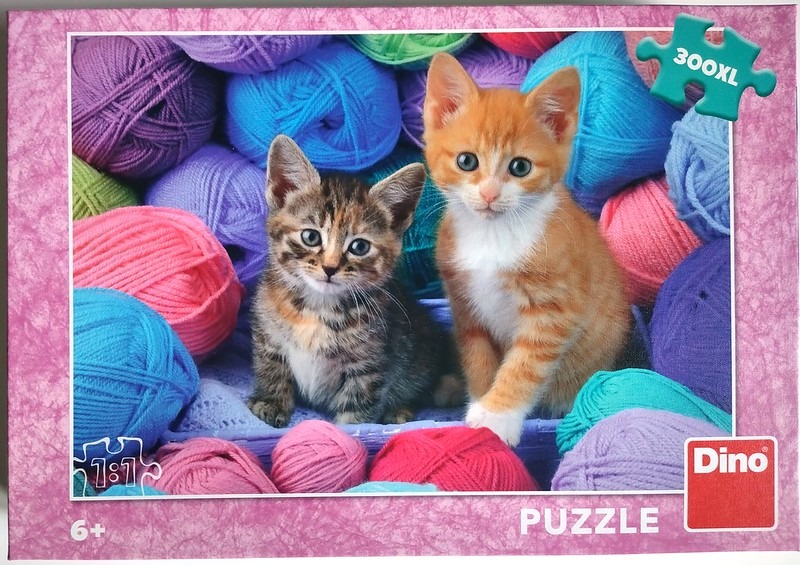 Two kittens sitting among a pile of colorful yarn balls