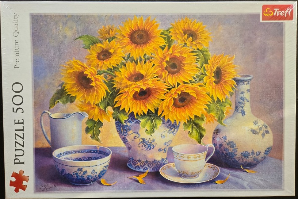 Still life oil painting of a bouquet of sunflowers in a decorative blue and white vase surrounded by ceramics.