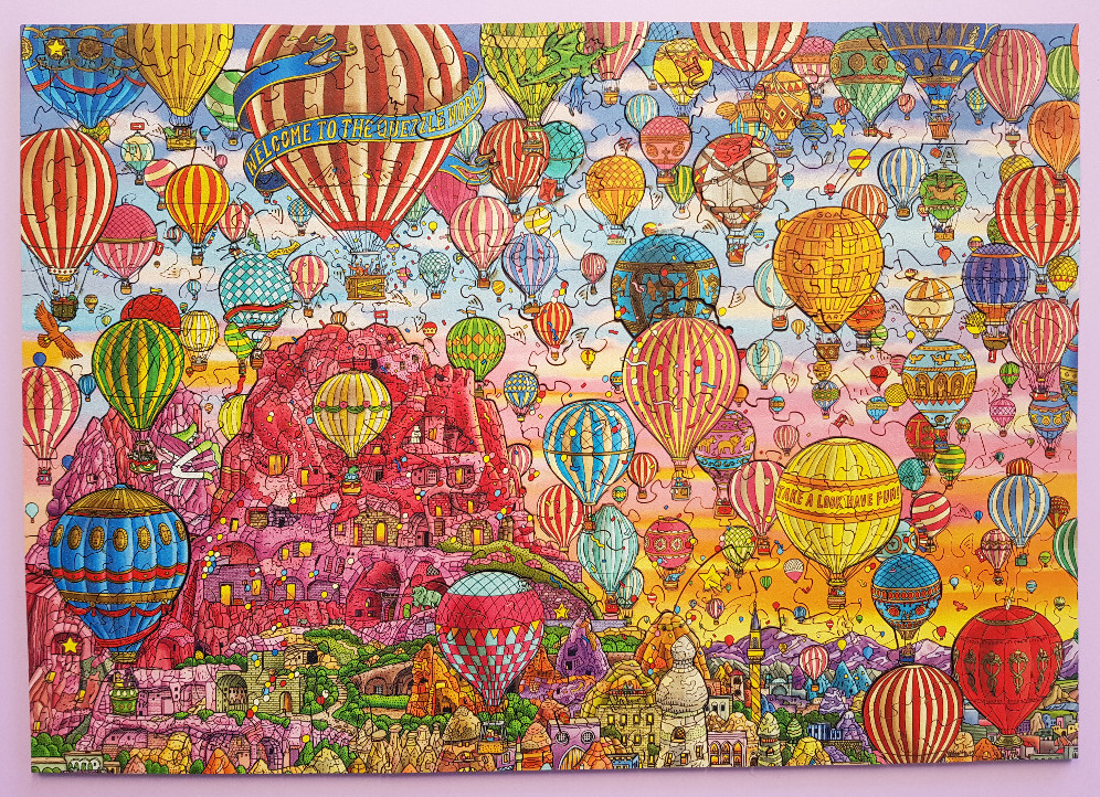 A whimsical illustration of countless hot air balloons floating over a rocky landscape with carved dwellings.