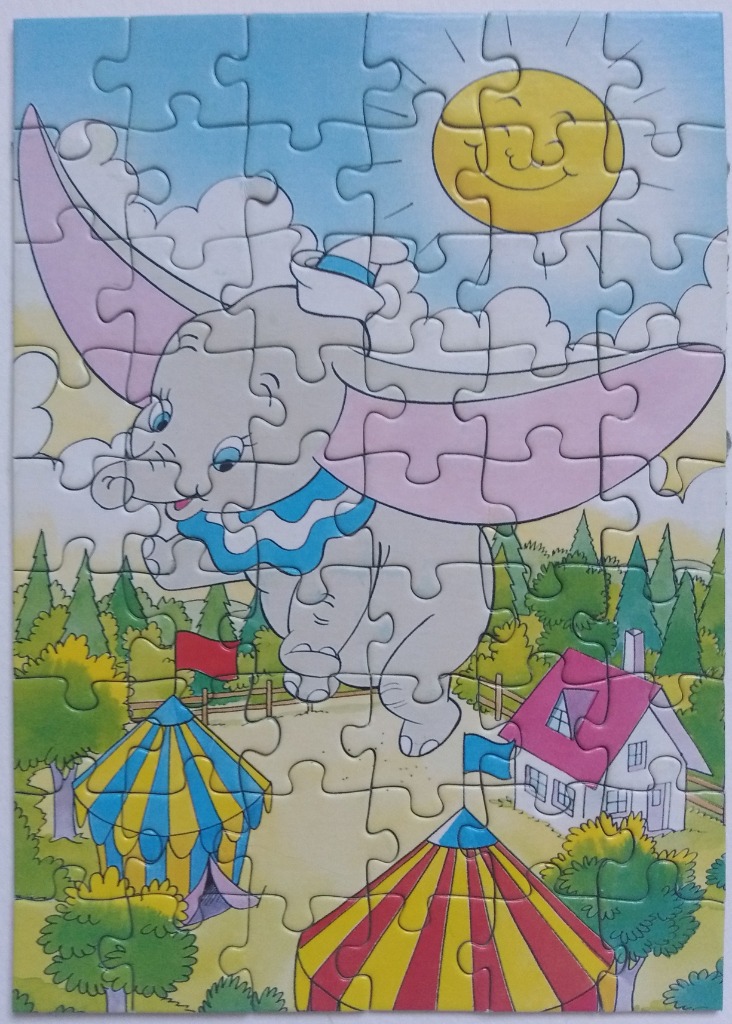 A cartoon of Dumbo the flying elephant soaring over a colorful circus ground and a small house.