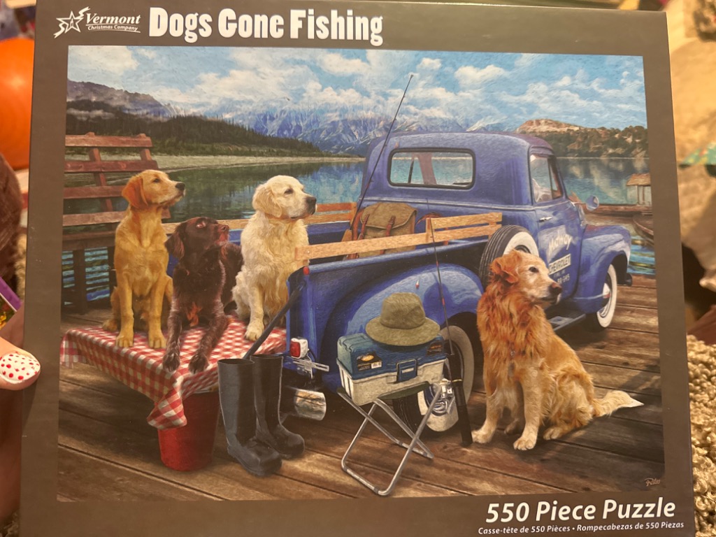 Four dogs waiting by a vintage blue truck on a wooden dock with fishing gear.