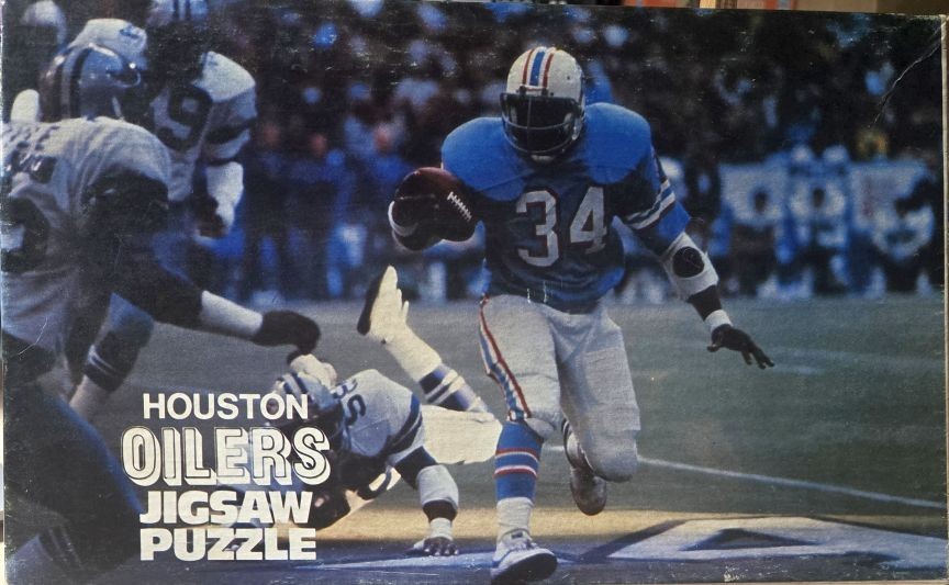 A Houston Oilers football player in a blue and white uniform running with the ball during a game.
