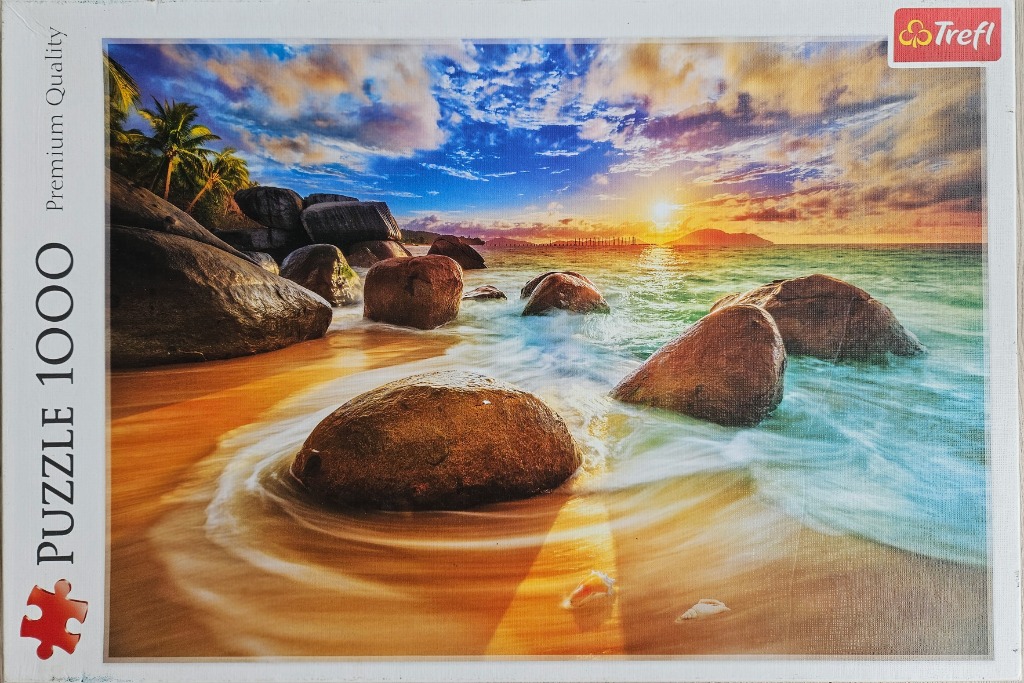 Tropical beach scene at sunset with large smooth boulders in the water