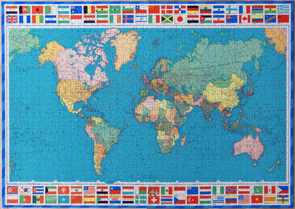 A vintage political world map surrounded by a border of various international flags.