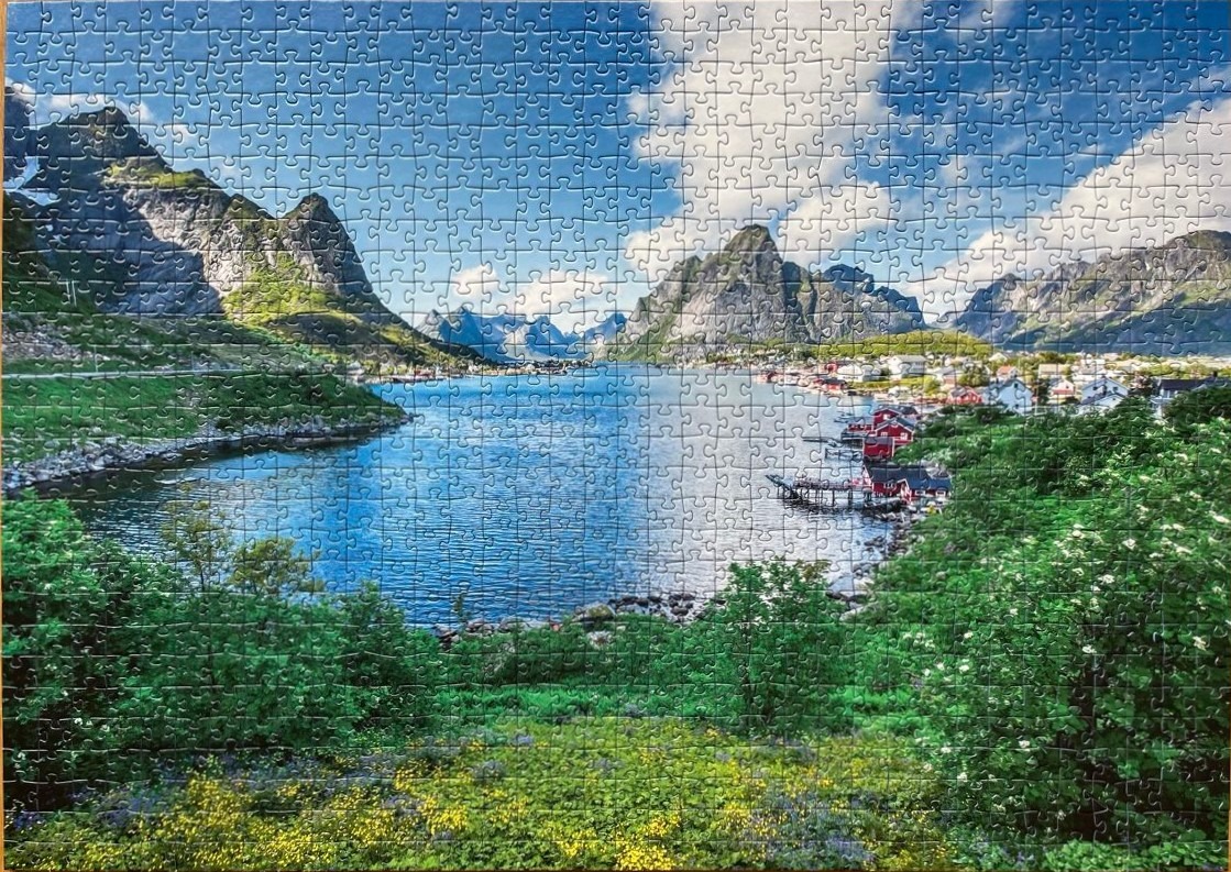 Scenic landscape of Reine, Norway featuring red cabins by a fjord with mountains in the background.
