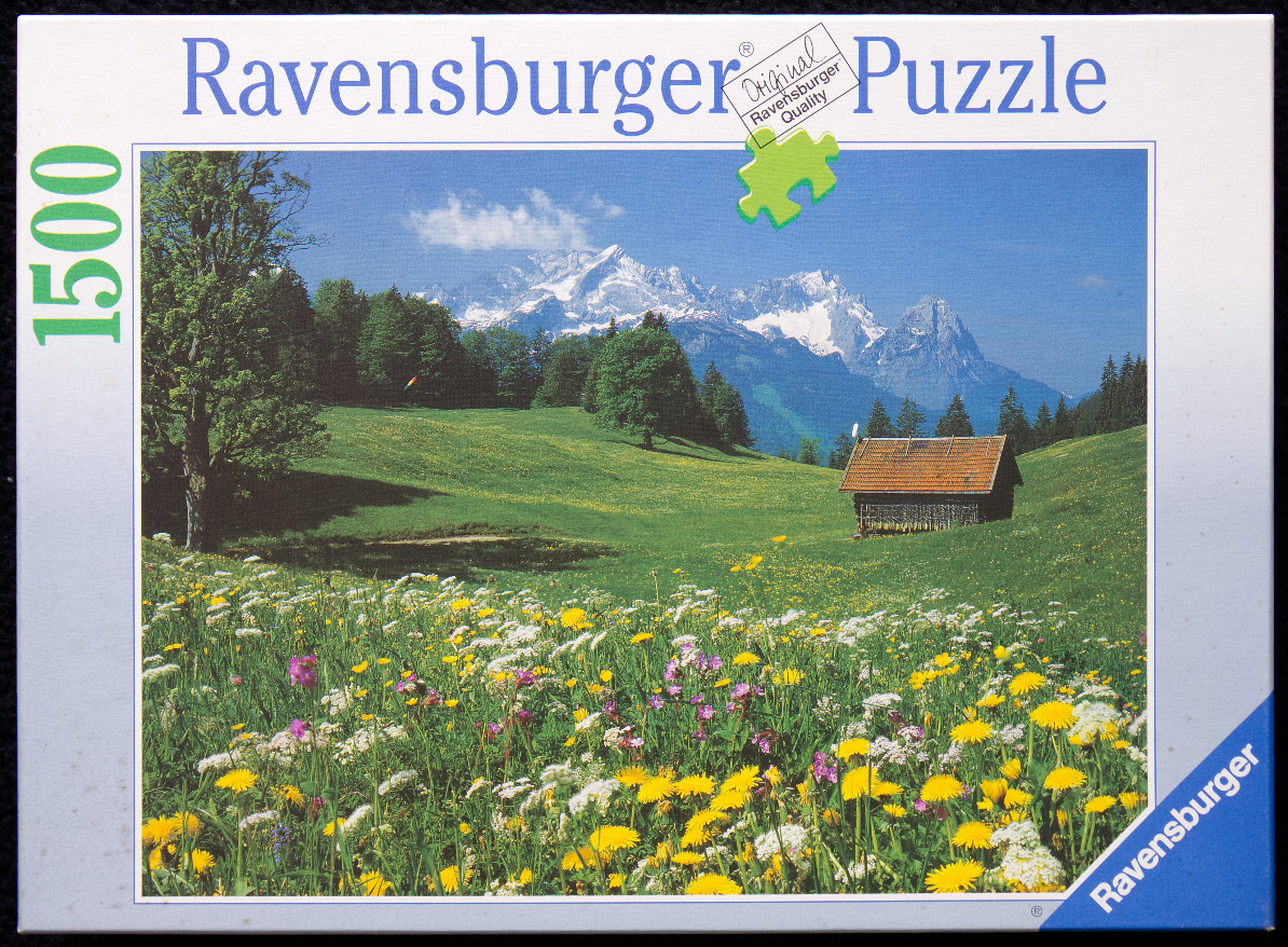 A lush alpine meadow with a wooden barn, wildflowers, and snow-capped mountain peaks in the background.
