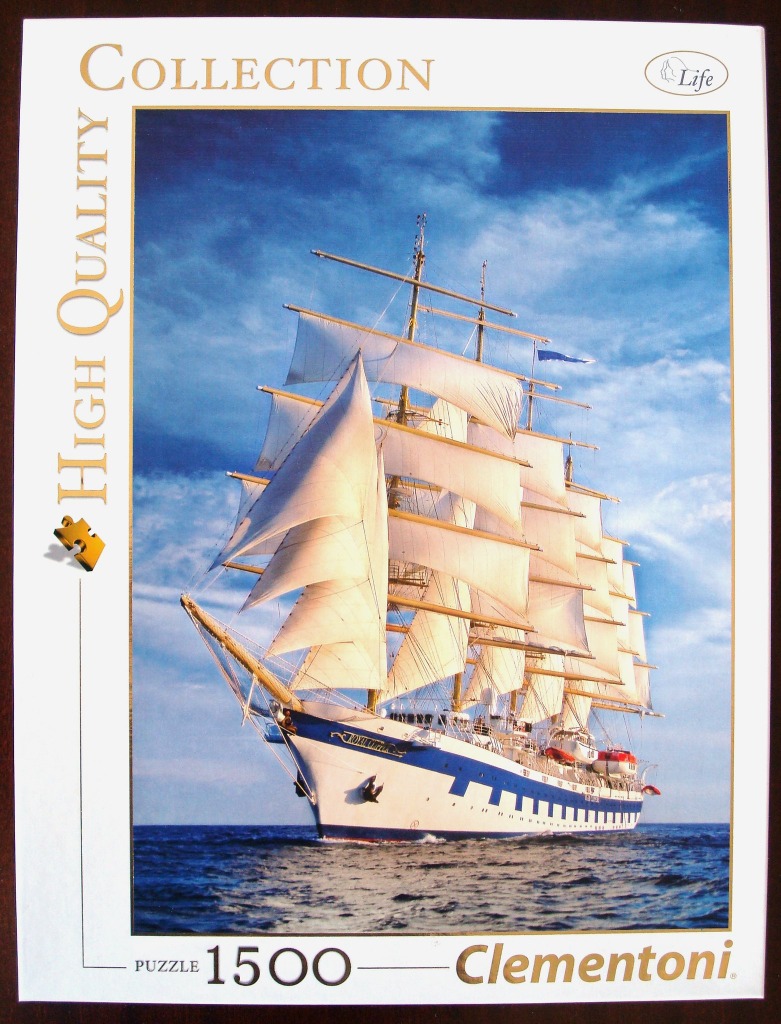 A large four-masted sailing ship with white sails unfurled on a blue sea under a sunny sky.