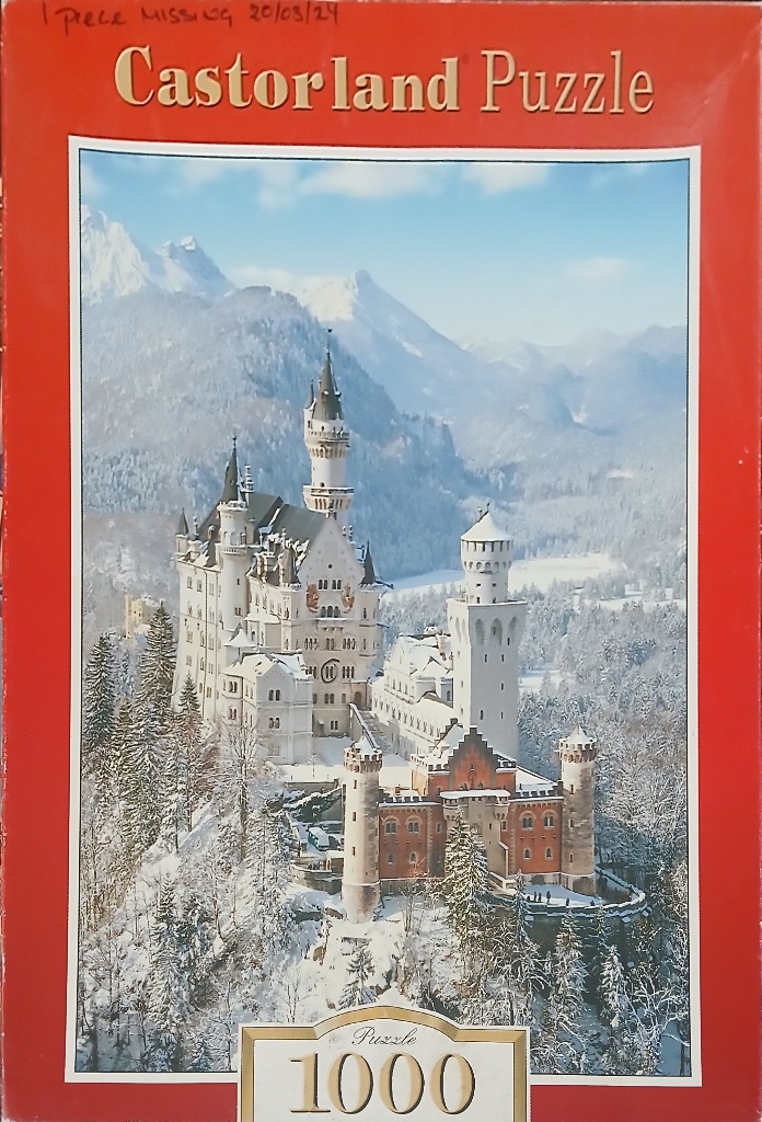 A panoramic photograph of Neuschwanstein Castle nestled in a snow-covered mountain landscape during winter.