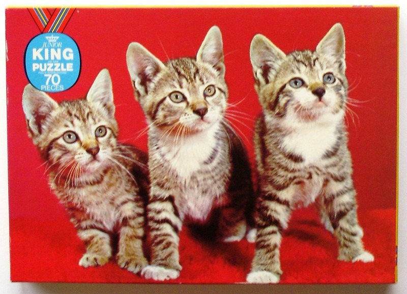 Three tabby kittens sitting against a vibrant red background.