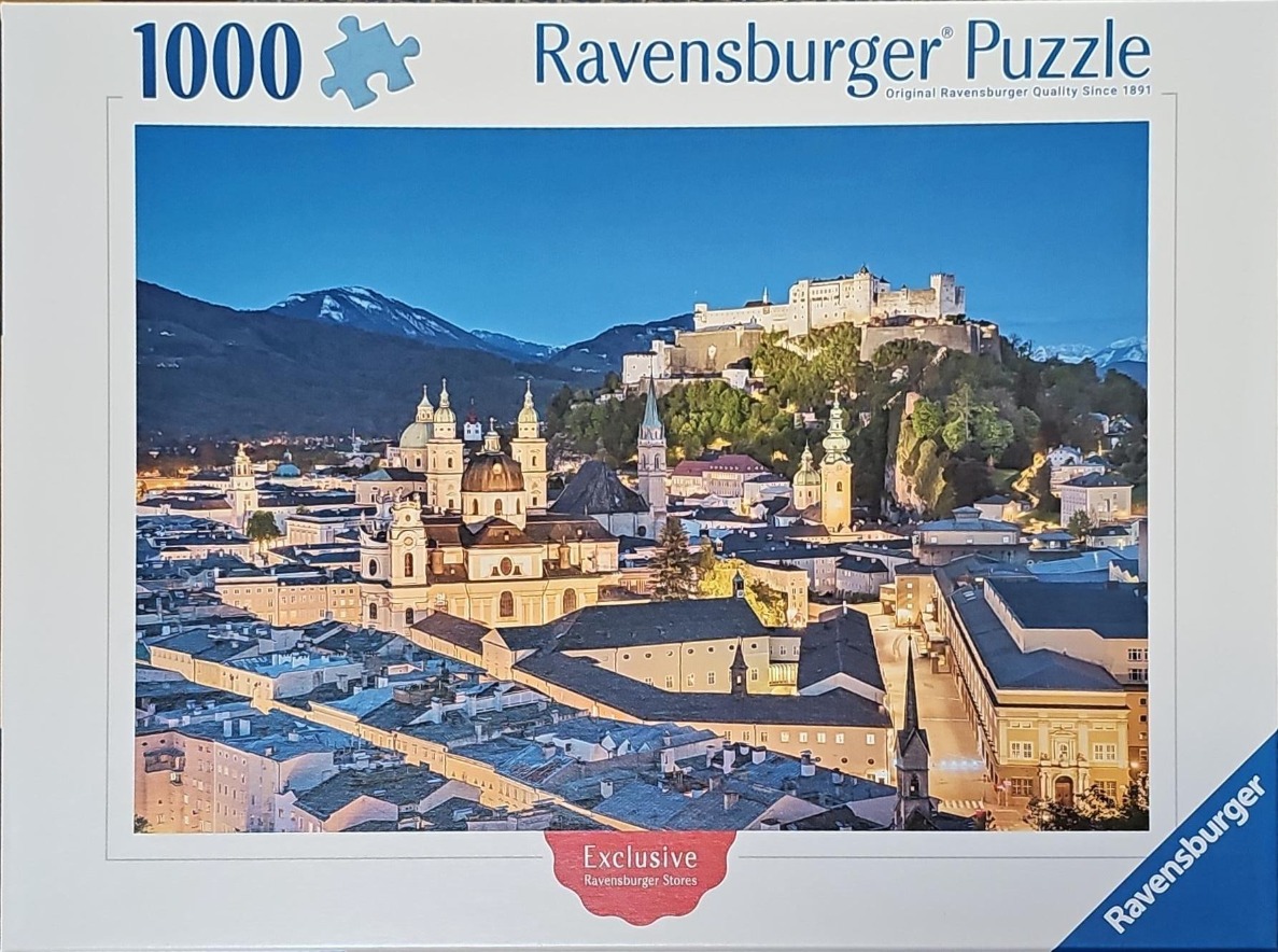 A twilight view of Salzburg, Austria, featuring the Hohensalzburg Fortress overlooking the city's historic rooftops.