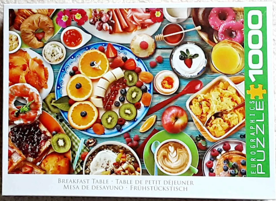 An overhead view of a wooden table covered in a generous, colourful breakfast spread featuring various fruits and pastries.