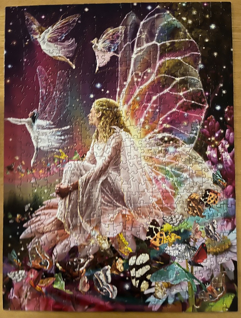 A fantasy illustration of a golden-haired fairy sitting on a large blossom surrounded by butterflies and smaller fairies.