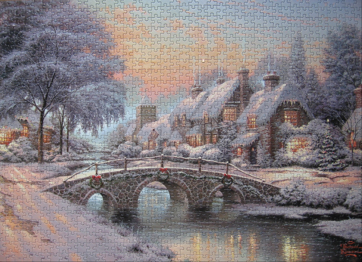 A cozy stone cottage in a snowy landscape with a three-arched stone bridge over a stream at twilight.