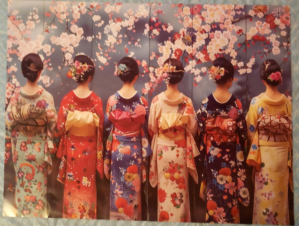 Six women in traditional Japanese kimonos standing in a row with their backs to the viewer beneath cherry blossoms.