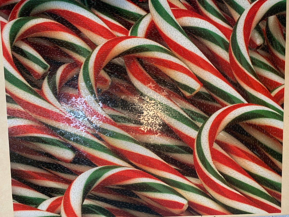 A close-up view of numerous overlapping candy canes with red, white, and green stripes.