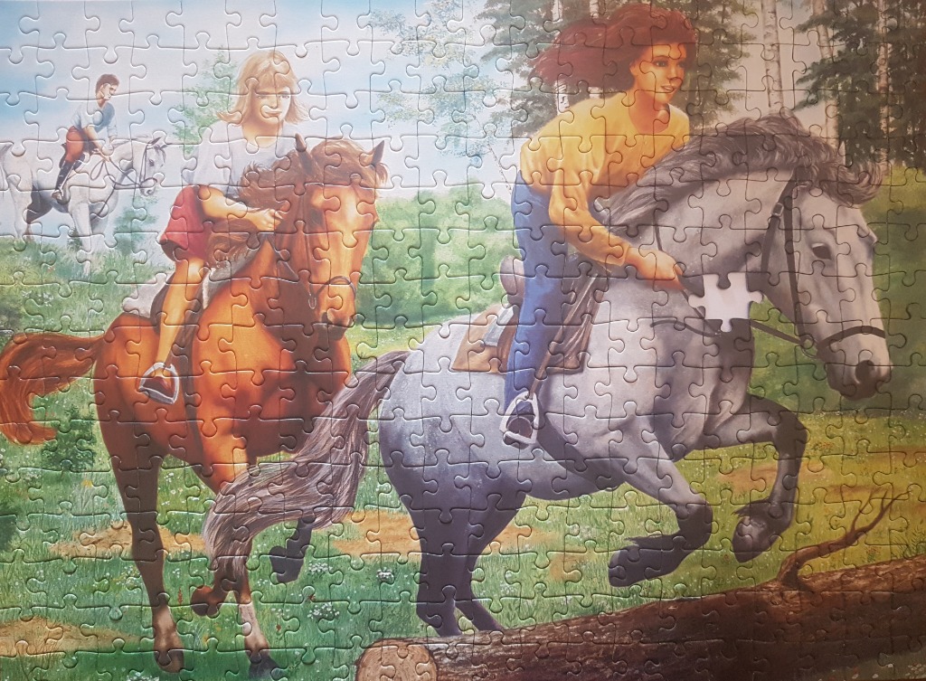 Three people riding horses through a sunlit, grassy forest meadow.
