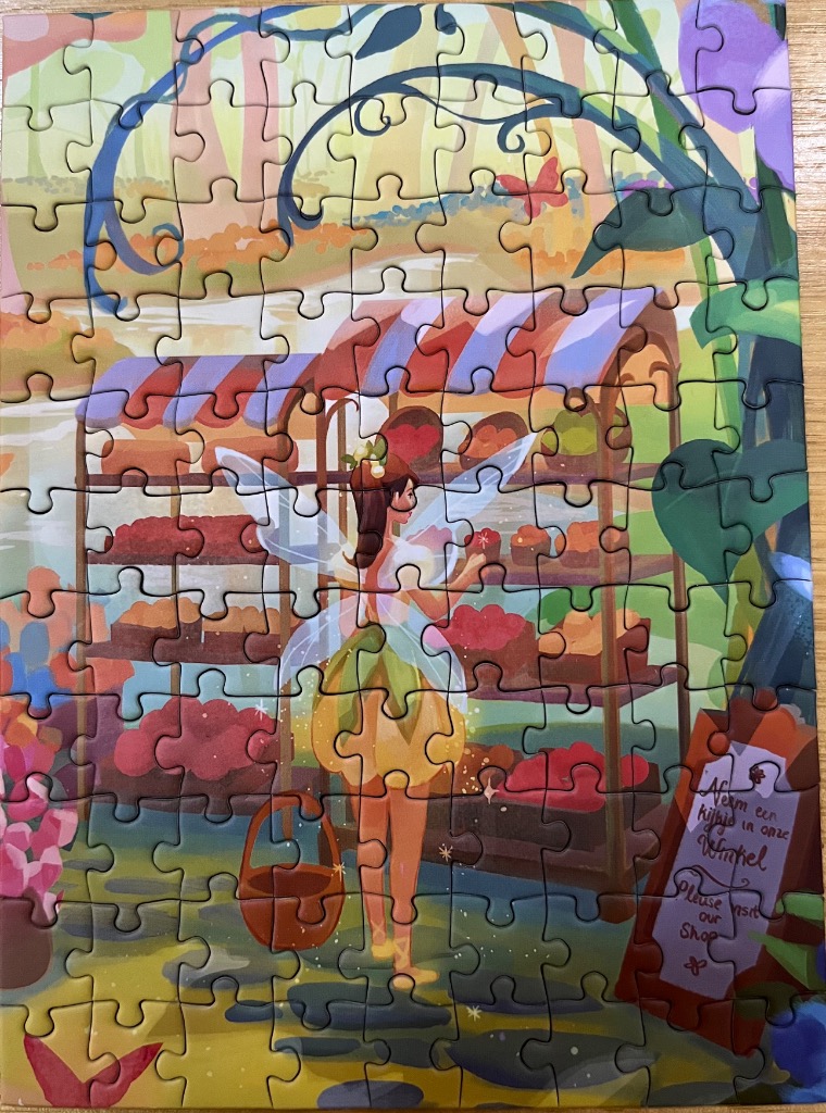 A fairy standing in front of a colorful market stall in a whimsical, painted illustration style.
