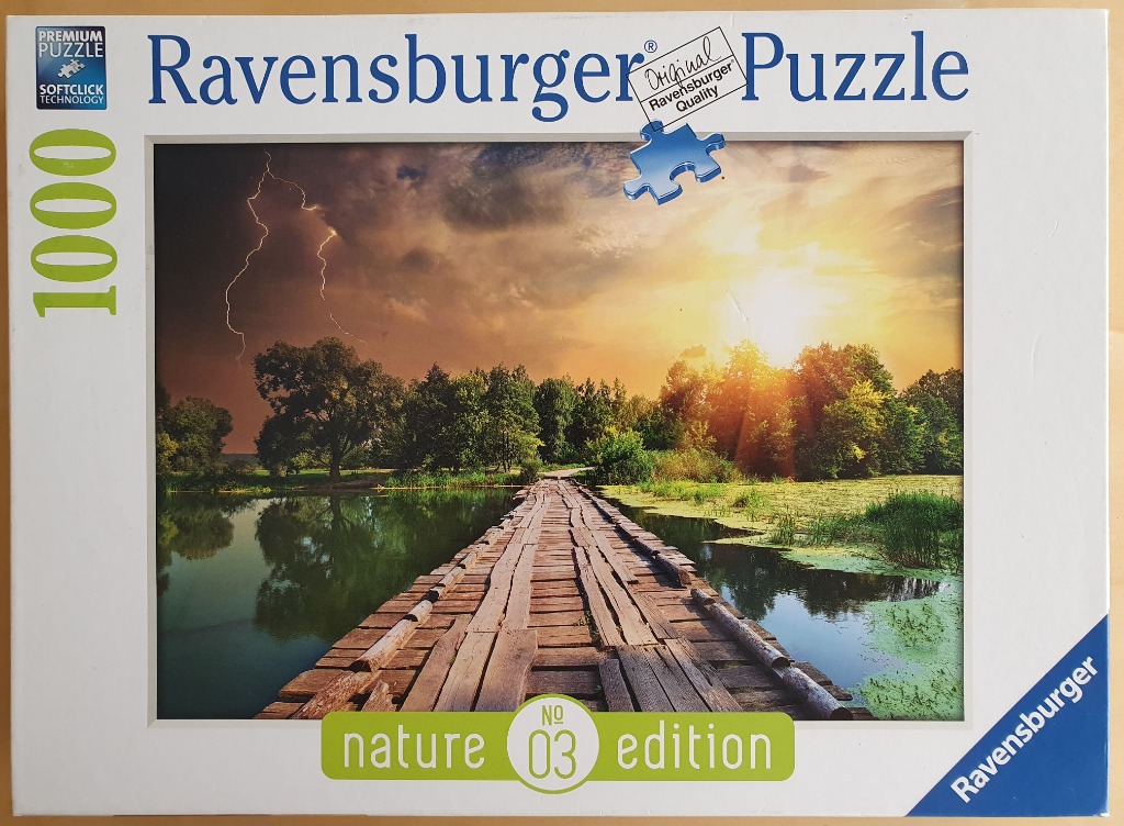 A wooden bridge crossing a lake at sunset with a dramatic thunderstorm in the background.