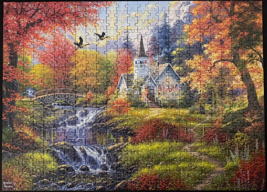 A peaceful country church nestled in a vibrant autumn forest with a waterfall and stream.