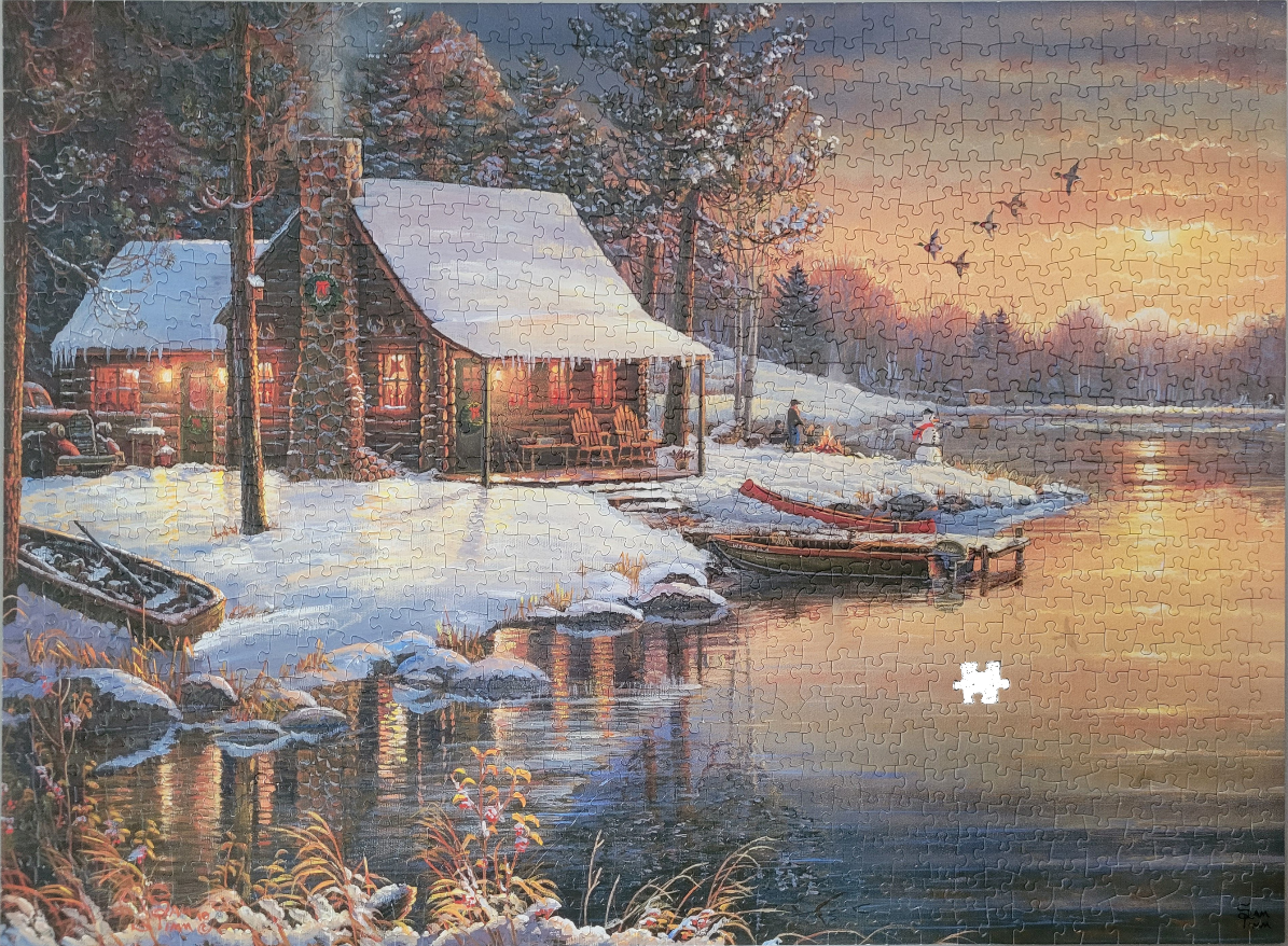 A cozy log cabin beside a snowy lake at sunset.