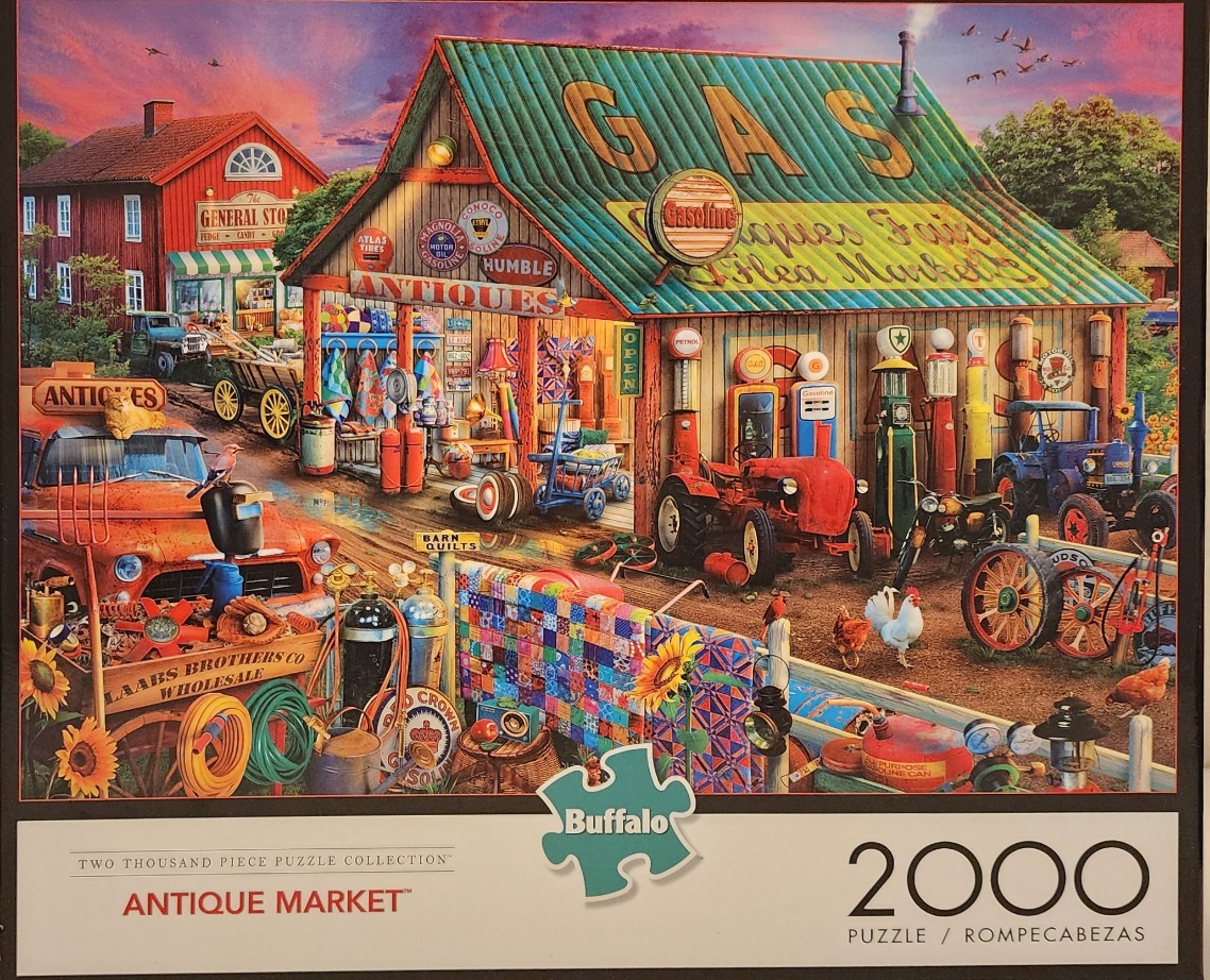 An outdoor antique market in front of a rustic gas station building at sunset.