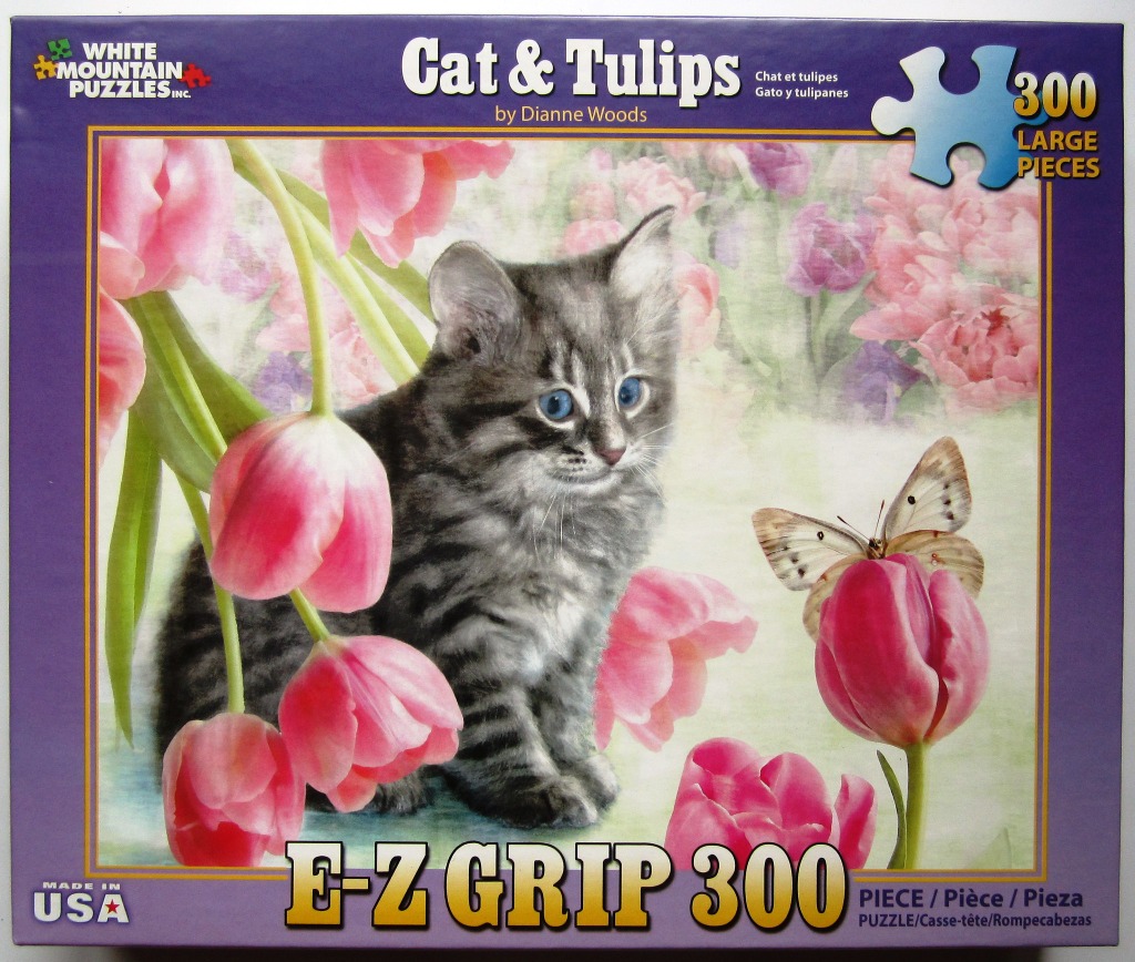 A fluffy grey tabby kitten sits amongst pink tulips with a butterfly landing on one bloom.