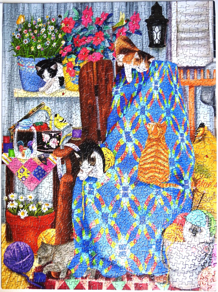 An illustration of several cats interacting with a vibrant blue patchwork quilt in a cozy craft room.