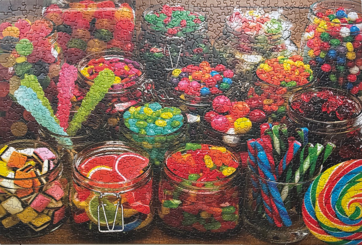 An assortment of glass jars filled with colorful candies, including lollipops, jelly beans, and gummy sweets.