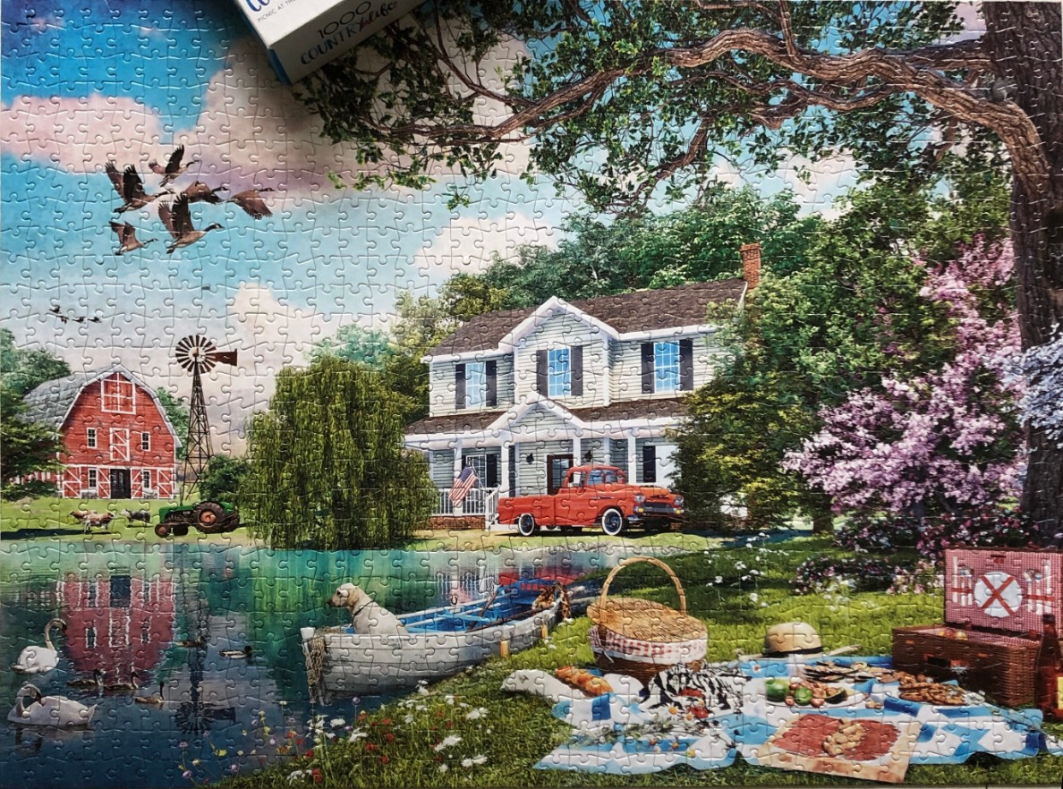 A peaceful country scene with a house, red barn, pond, and a picnic in the foreground.