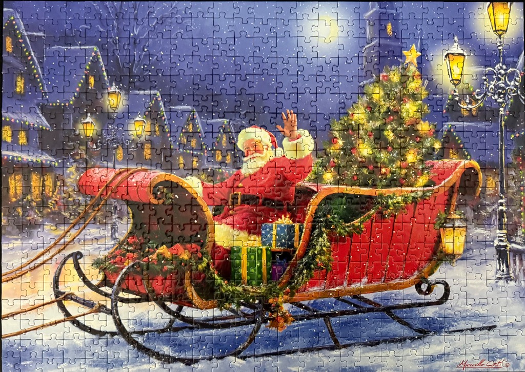 Santa Claus waving from a red sleigh in a snowy village at night