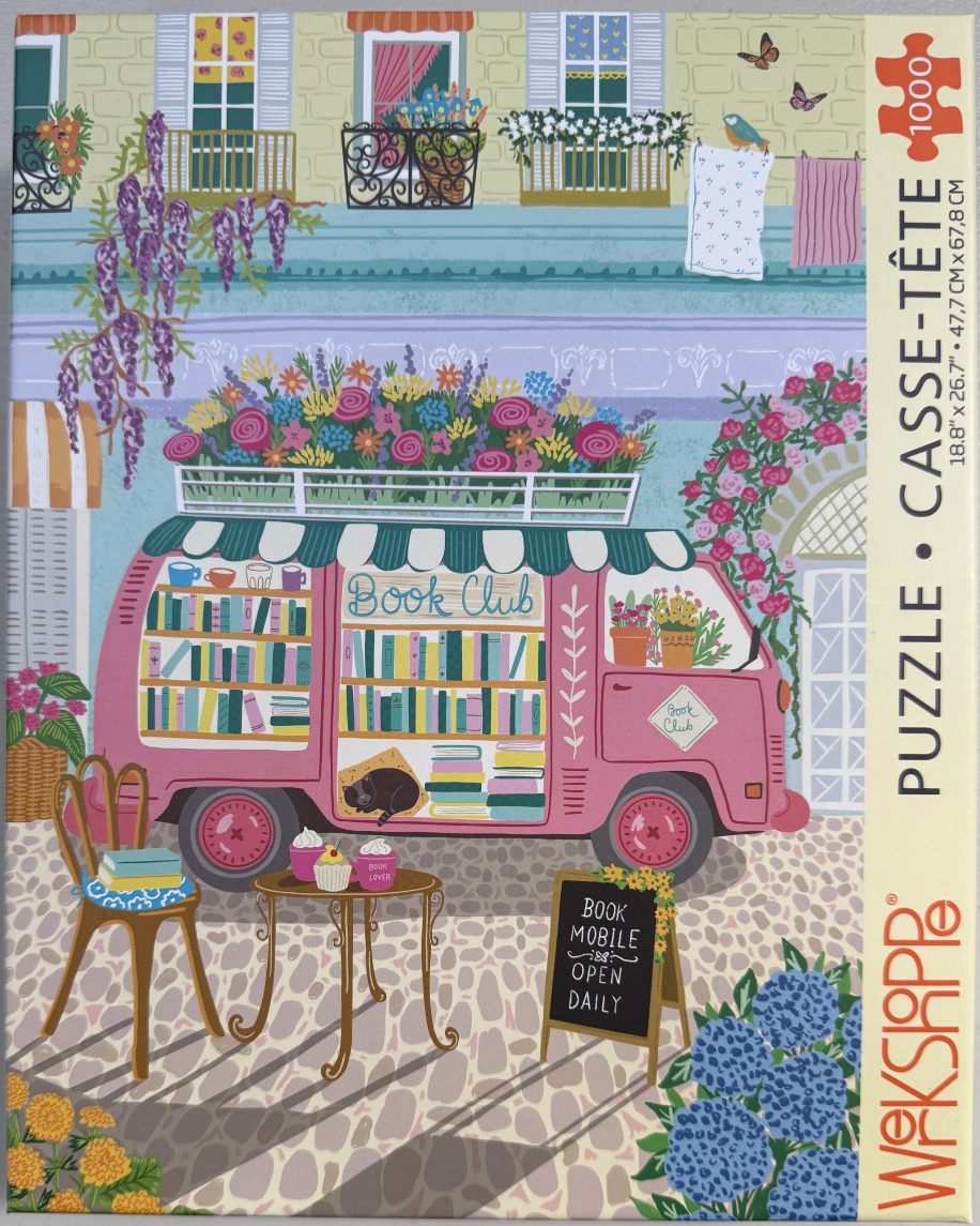 A whimsical pink van converted into a mobile bookstore parked on a cobblestone street.
