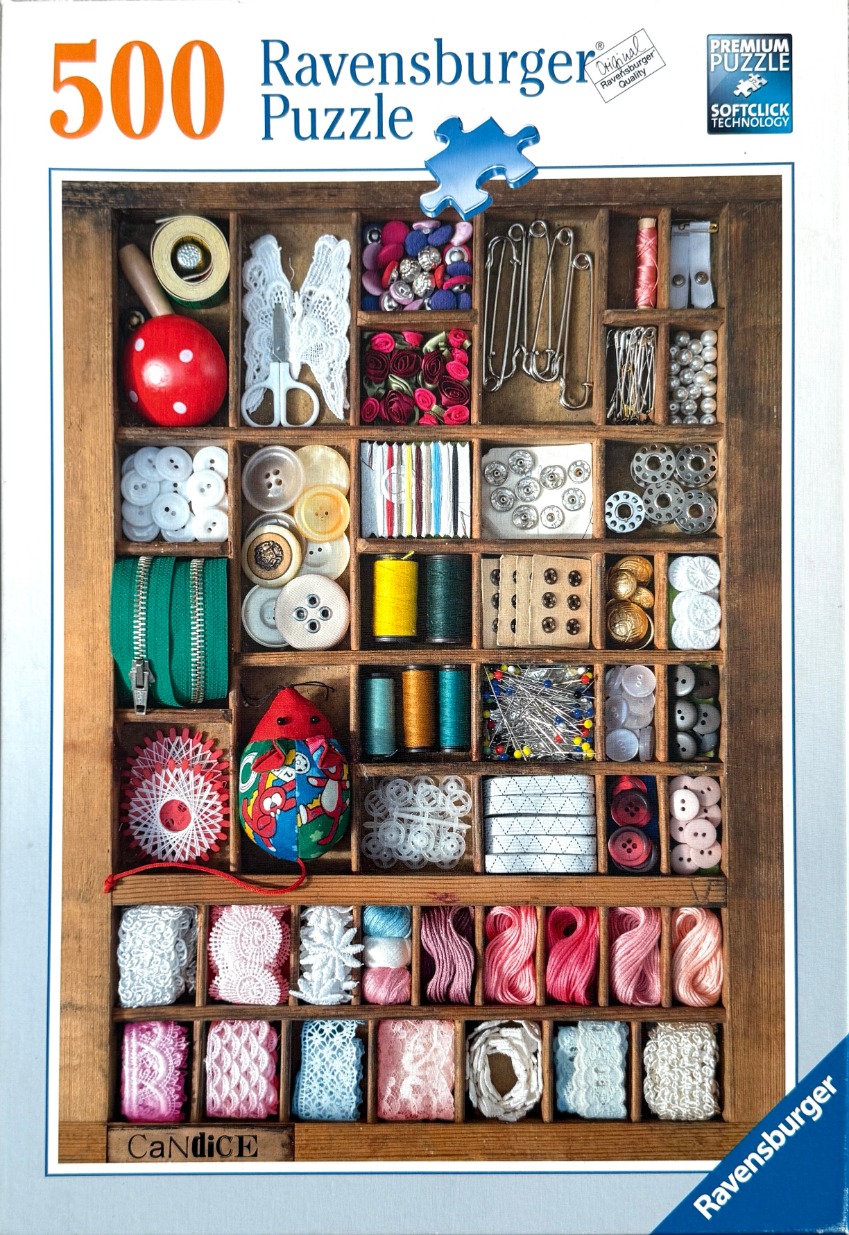 A wooden printer's tray filled with organized sewing notions and craft supplies like thread, buttons, and lace.