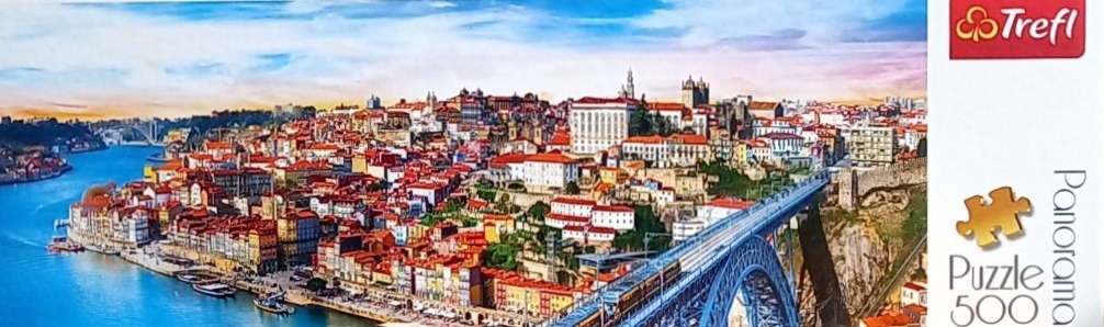 Panoramic view of the city of Porto, Portugal, featuring the Douro River, colorful riverside buildings, and a bridge.