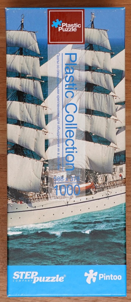 A tall ship with white sails sailing on deep blue water.