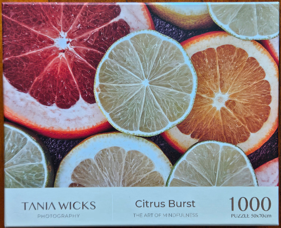 A close-up photographic arrangement of various sliced citrus fruits including grapefruit, orange, and lime.