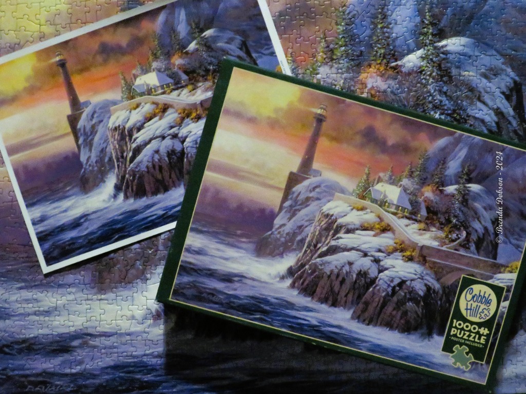 A lighthouse on a snowy cliff at sunset surrounded by rough ocean waters.