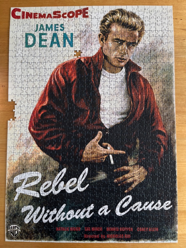 A vintage film poster featuring James Dean in a red jacket for the movie Rebel Without a Cause.