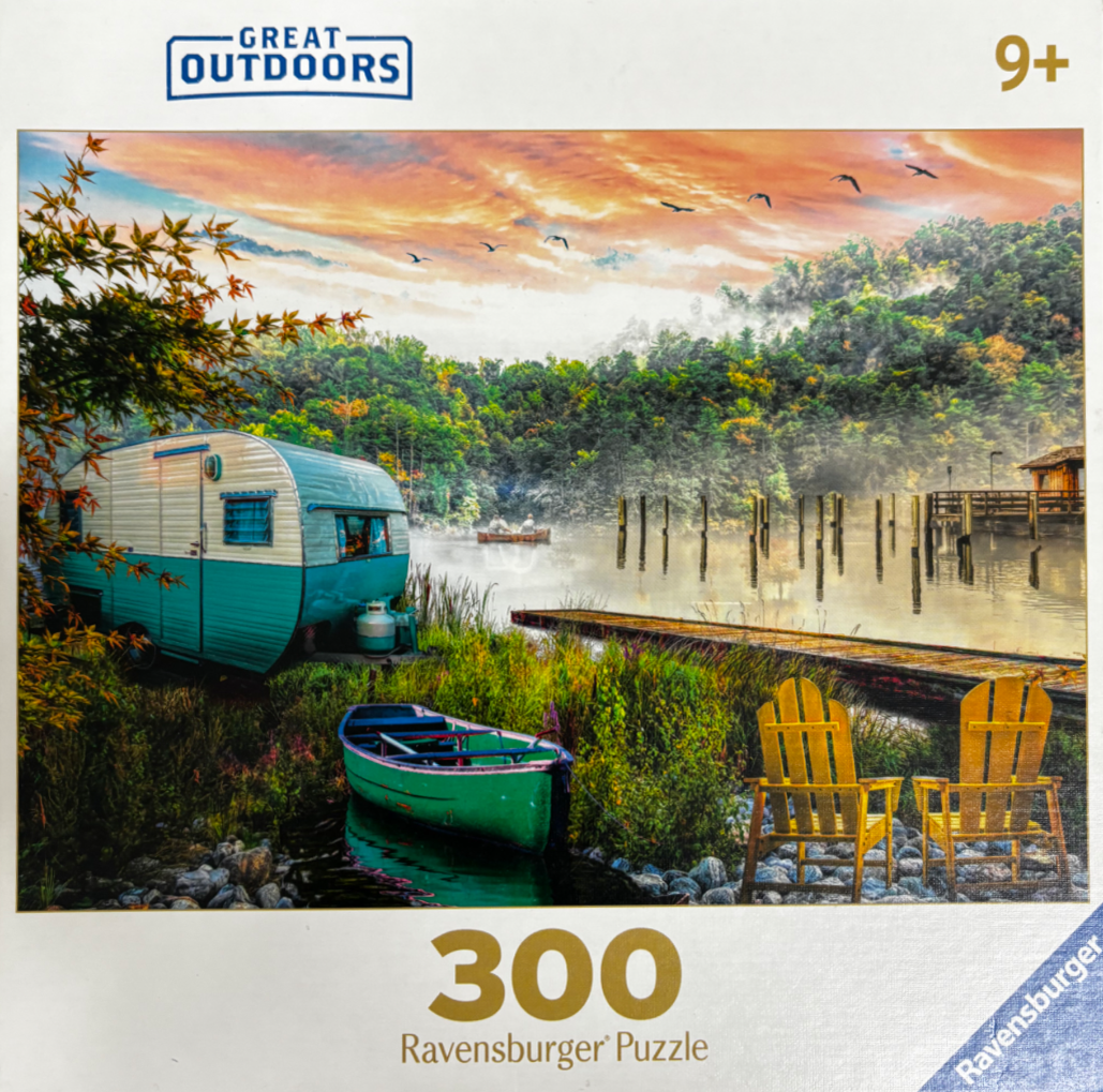 A vintage turquoise camper and rowboat by a misty lake at sunrise with yellow Adirondack chairs on the shore.