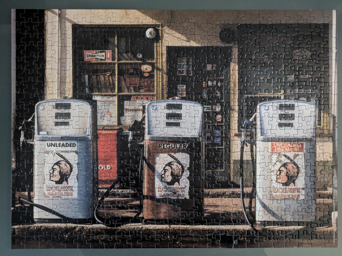 Three vintage Mohawk Gasoline pumps in front of an old garage shop.