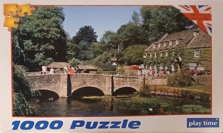 Stone arched bridge crossing a river by an ivy-covered English inn.