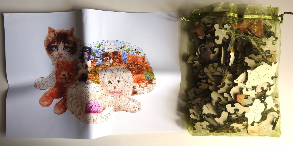 A sheet showing an illustration of kittens alongside a drawstring organza bag filled with puzzle pieces.