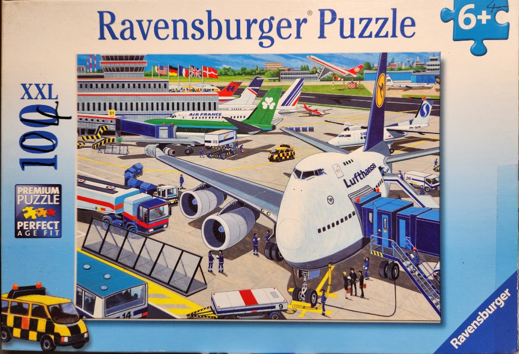 A bustling airport scene featuring a large Lufthansa jumbo jet at the terminal gate surrounded by service vehicles.