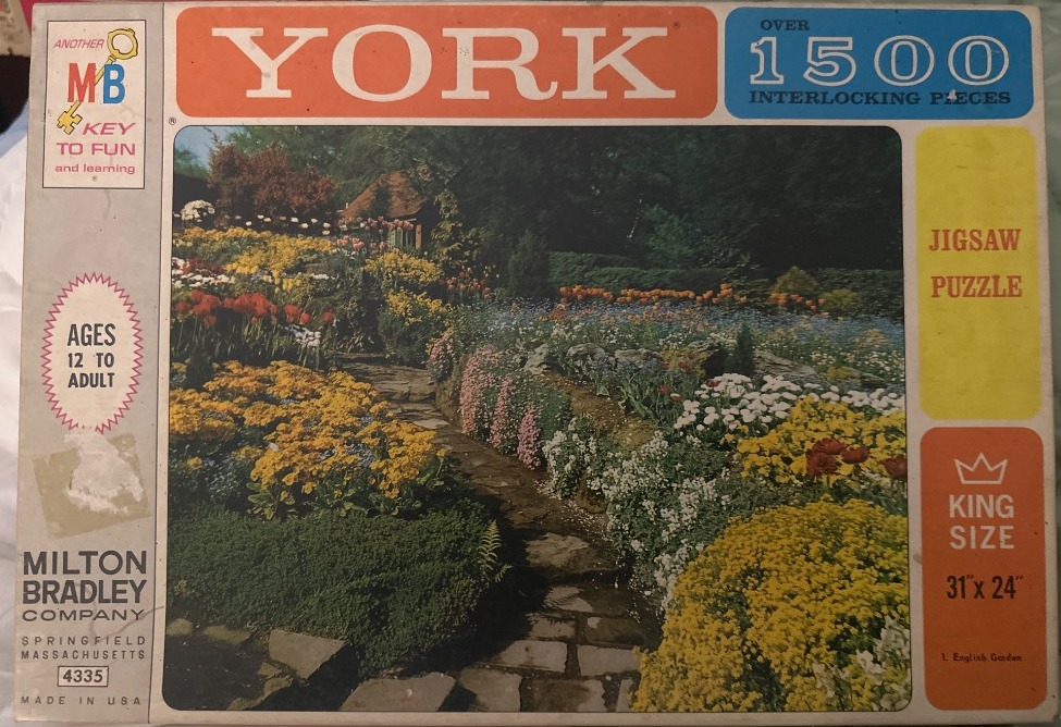A lush, colorful English garden with a stone path winding through vibrant flower beds.