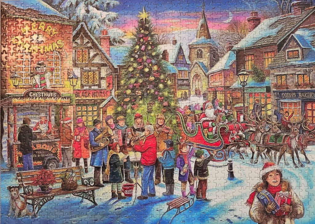 Festive snowy village square with a large Christmas tree, carolers, and Santa in his sleigh.