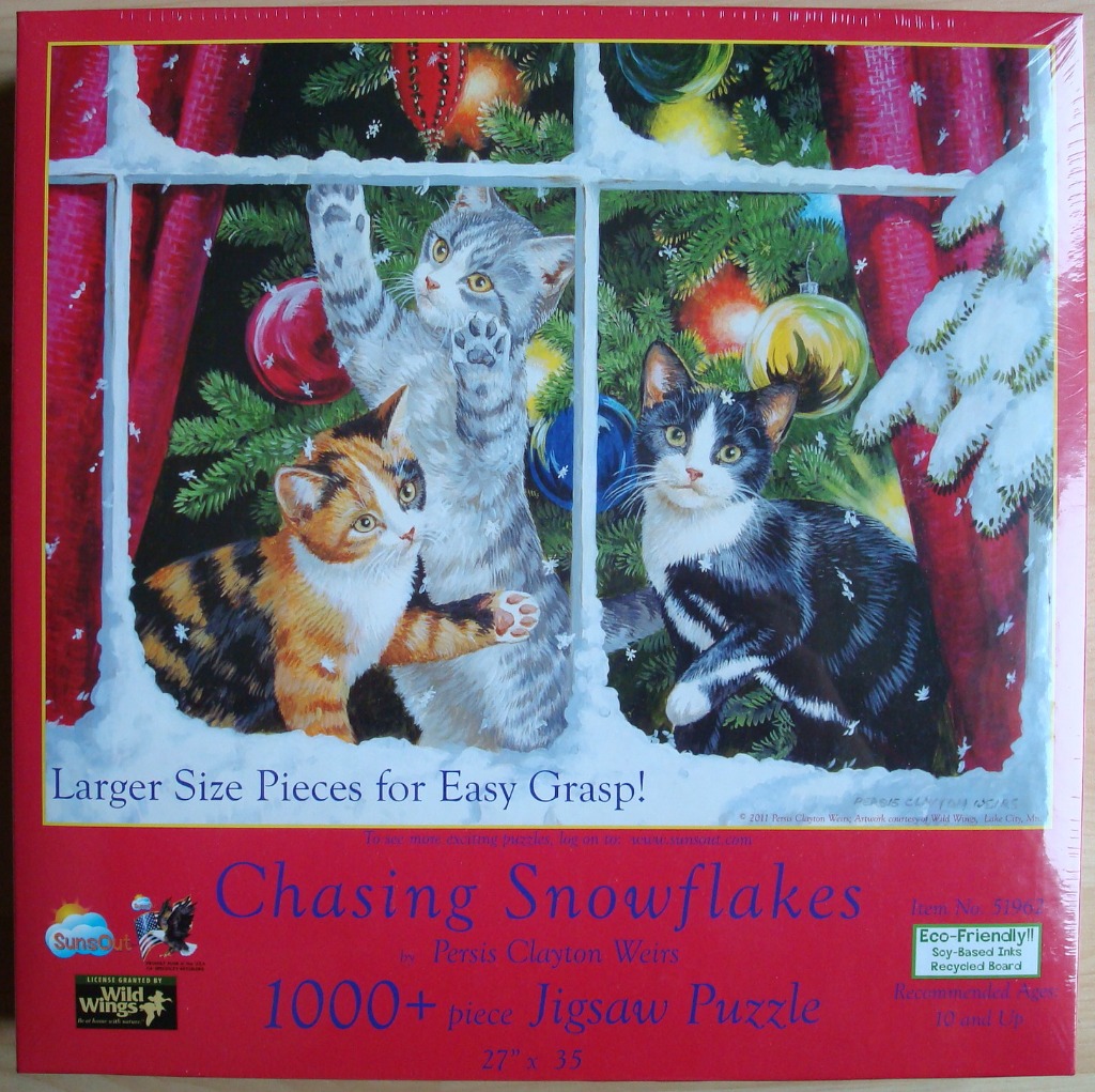 Three kittens looking through a snowy window at a decorated Christmas tree.