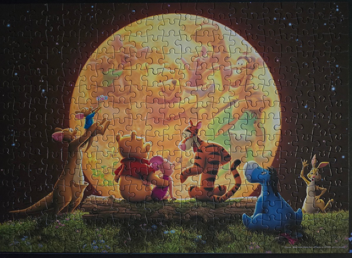 Winnie the Pooh and friends gathered on a log at night, silhouetted against a giant glowing full moon.