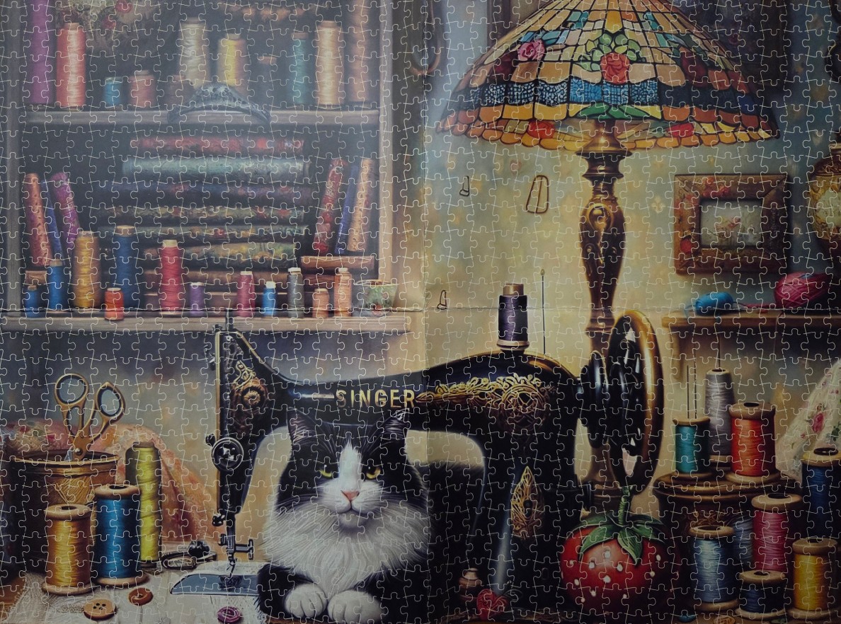 A tuxedo cat sitting behind a vintage sewing machine in a cozy, thread-filled craft room.