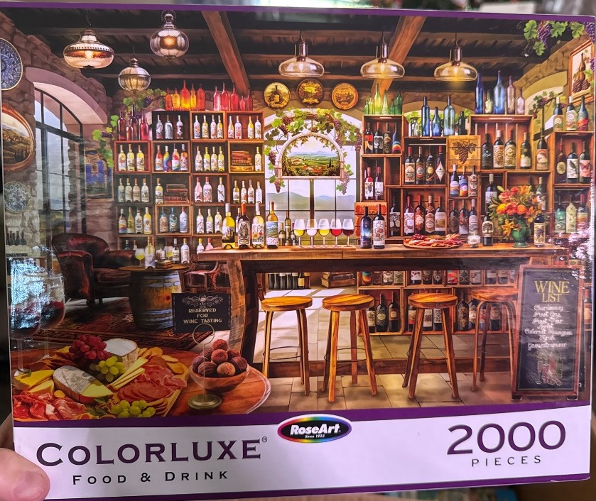A cozy rustic wine cellar and tasting room featuring wooden shelves filled with wine bottles and a charcuterie platter.